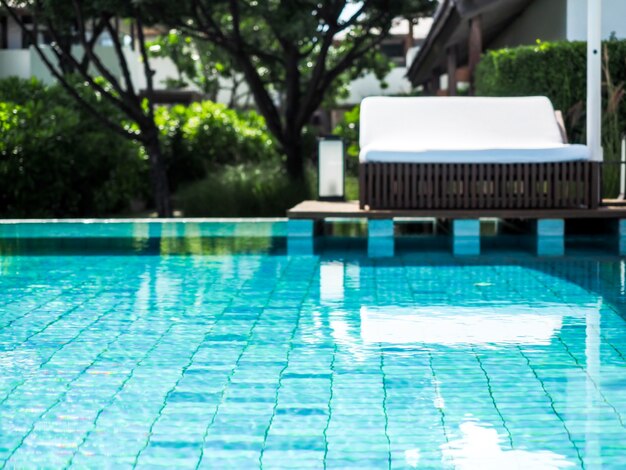 Photo blurred view of pool with white sunbed in the resort.