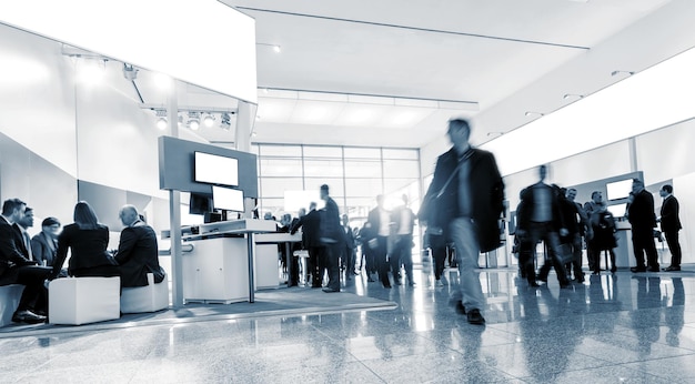 Blurred visitors walking at a entrance on a trade fair, with copy space on a banner. ideal for websites and magazines layouts