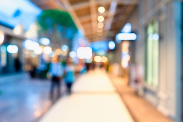 Blurred walking people in downtown shopping street at twilight with bokeh 