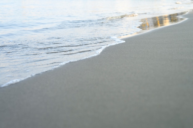 Blurred wave of the sea on the evening sand beach