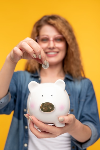 Blurred woman putting coin in money box