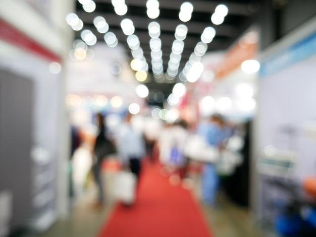 Photo blurry background of exhibition expo with crowd people in convention hall