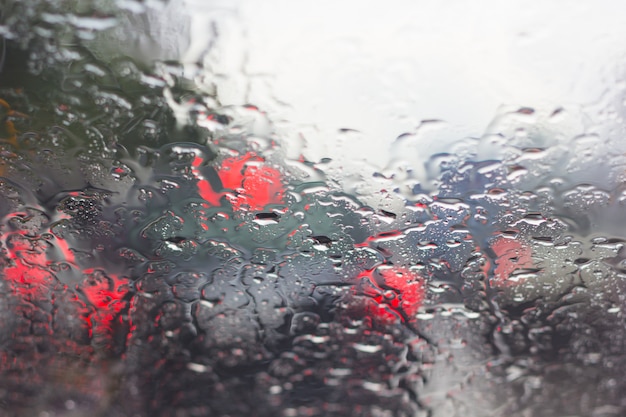 Blurry car silhouette seen through water drops on the car windshield