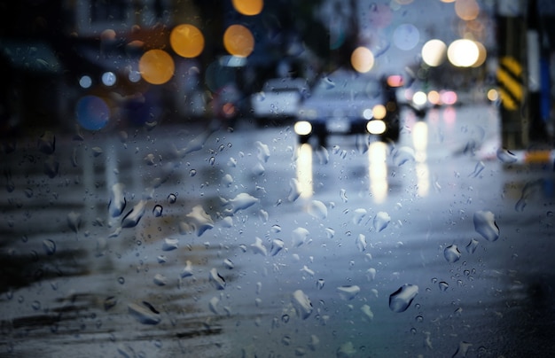 Blurry cars run through wet road in city during hard rain fall\
at night.