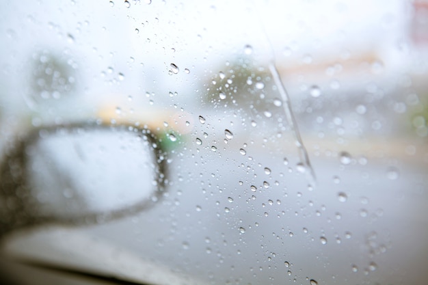 Blurry drop of rain on car side mirror on the road 