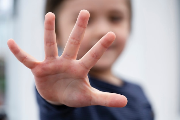 Blurry face of little boy showing five fingers,kid showing five numbers with fingers