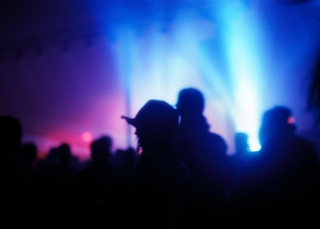 Blurry shot of a lot of people at a concert with spotlights in the background