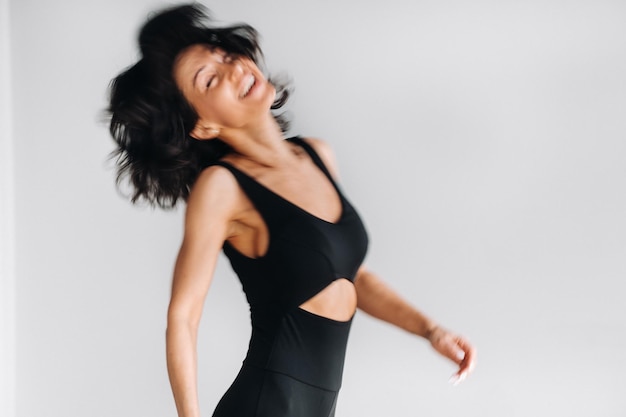 A blurry silhouette of a woman in black sportswear is engaged in dynamic kali meditation in the yoga hall