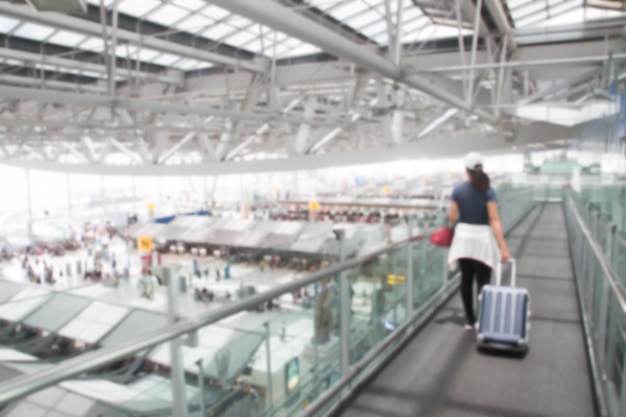 Blurry of woman with luggage on walk way in the airport