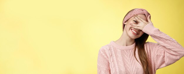 Photo blushing cute girl feeling positive smiling happy joyful covering eyes with palm peeking through