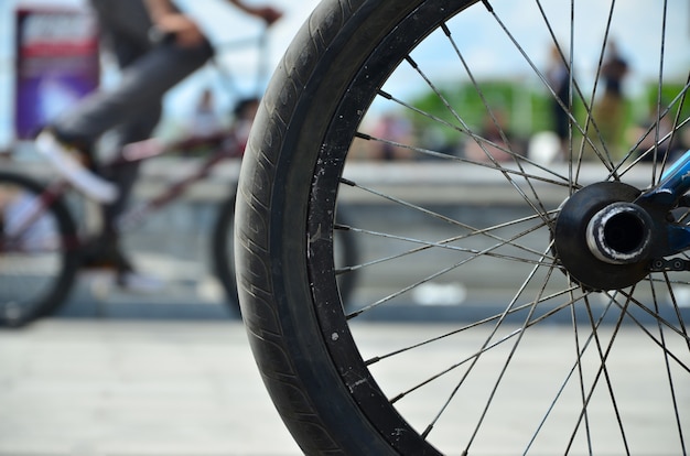 A BMX bike wheel against the backdrop of a blurred street with cycling riders. 