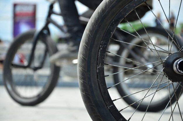 A BMX bike wheel against a blurred street with cycling riders. Extreme Sports Concept