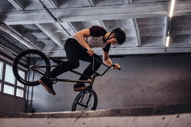 Bmxフリースタイル。屋内のスケートパークで彼の自転車でトリックを作る若いBMX