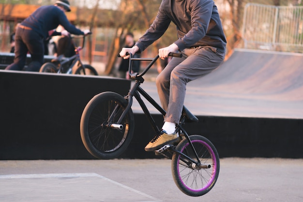 Bmx 라이더는 스케이트 보드에서 BMX를 속입니다. Bmx에서 저녁 훈련. 자전거가 뒷바퀴를 타고 이동합니다. Bmx 개념