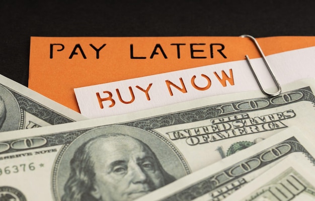 BNPL of Buy Now Pay Later concept Dollarbiljetten en label met bericht op zwarte achtergrond