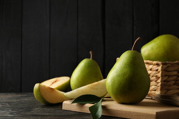 Board and basket with green pears on wooden table