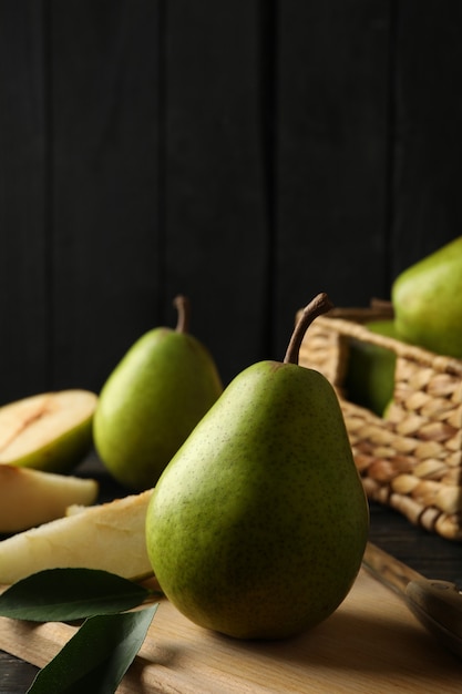 Board and basket with green pears on wooden