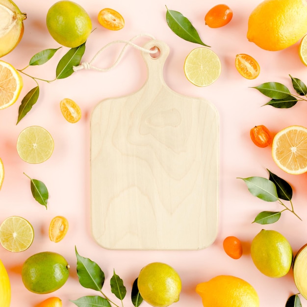 Board frame and summer tropical fruits orange lemon lime mango on pink background food concept flat