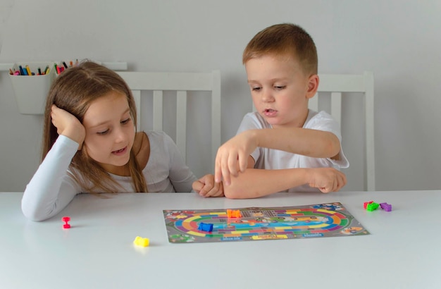 A board game and the concept of children's leisure Children are playing a board game Portrait of two cheerful children playing with colorful cubes Selective focus