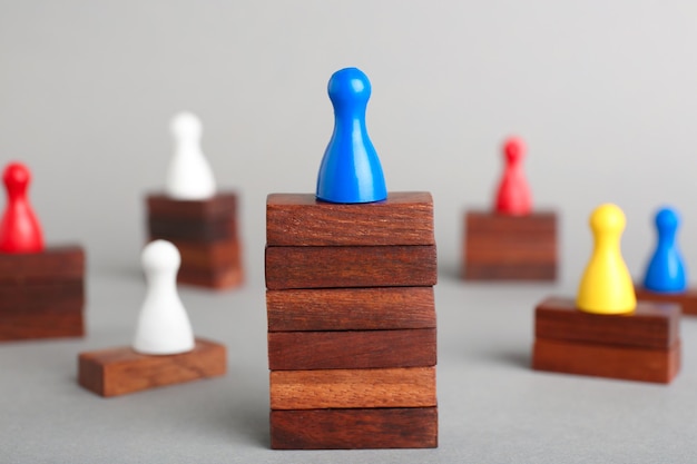 Фото Кусок настольной игры на деревянных блоках, доминирующих над другими фигурами на сером фоне концепция победы