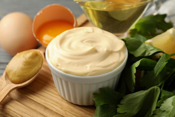 Photo board with bowl of mayonnaise and ingredients for cooking on wooden background