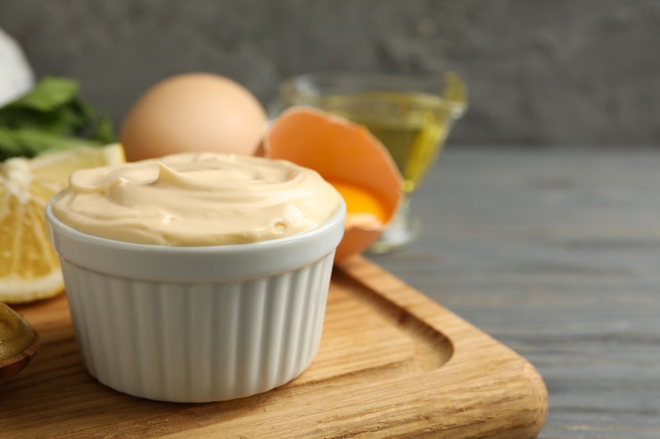 Photo board with bowl of mayonnaise and ingredients for cooking on wooden background