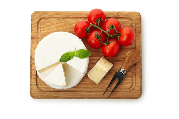 Board with camembert cheese, basil, fork and tomato isolated on white background