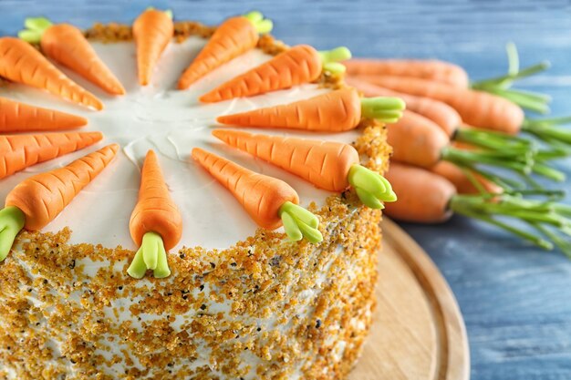 Board with delicious carrot cake on table closeup