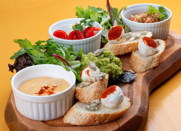 Photo board with delicious snacks guacamole eggplant with dor blue sheep cheese with paprika eggplant puree