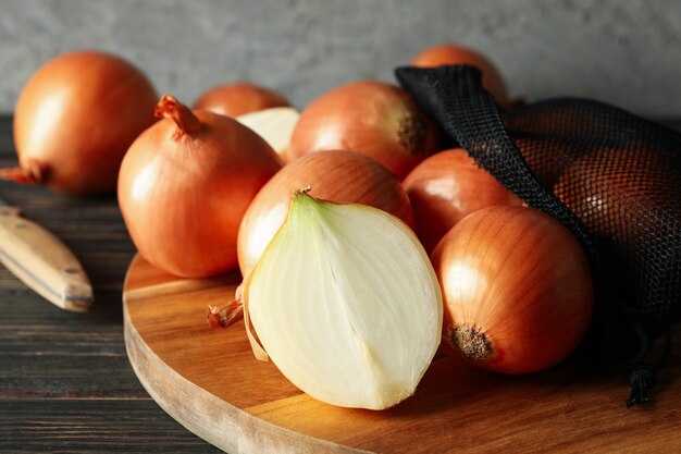 Board with fresh onion on wooden background