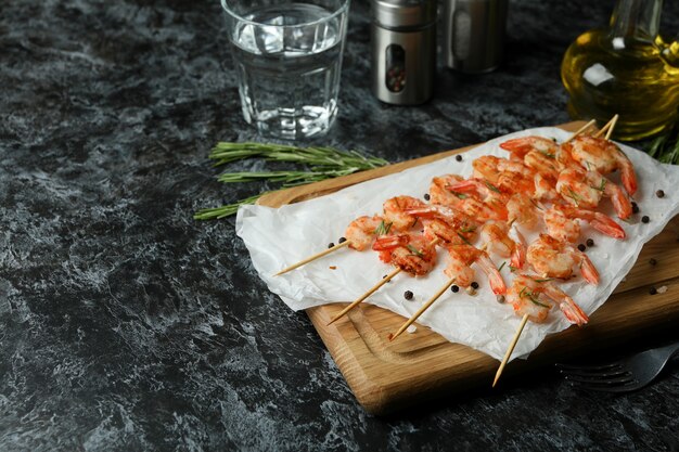 Board with grilled shrimps on black smokey table