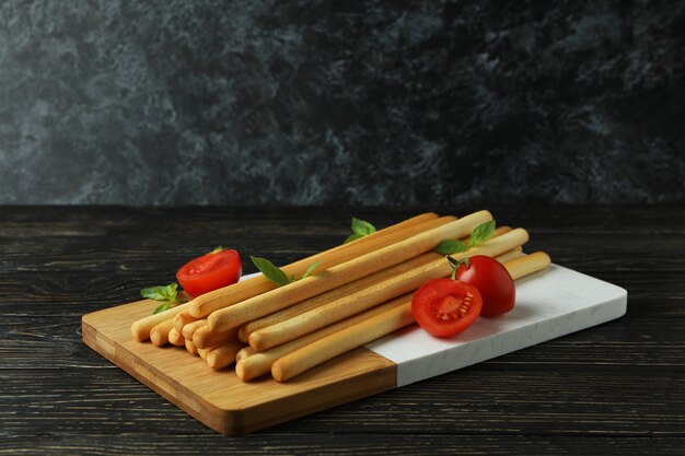 Board with grissini breadsticks on wooden table