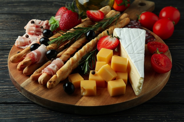 Board with grissini and snacks on wooden background