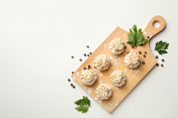 Board with khinkali, spices and flour on white table