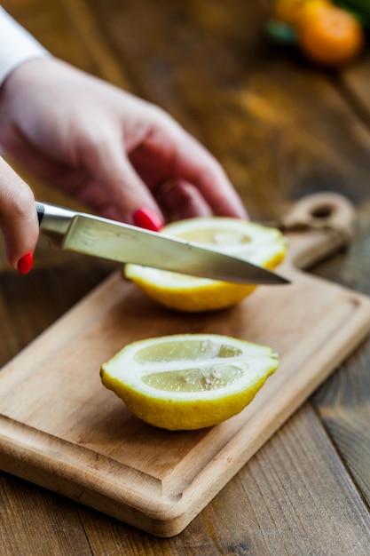 Tavola con limone e lime per affettare, preparare per cucinare, insalate e antipasti, succo di limone, decorare piatti, cucinare, uomo che taglia un limone, con in mano un coltello da cucina, tagliare un lime