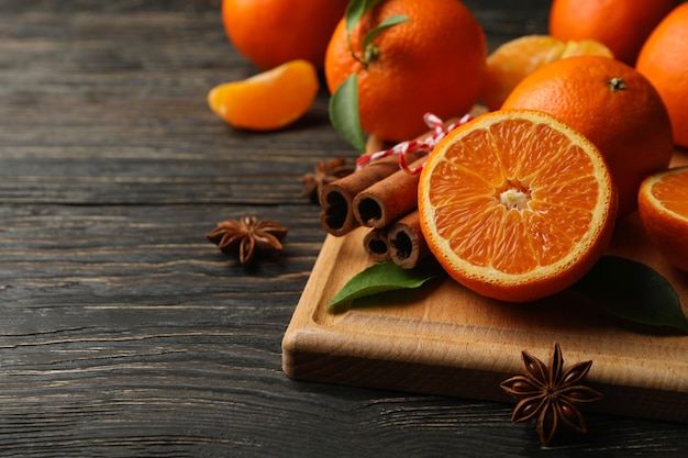 Board with mandarins and cinnamon on wooden