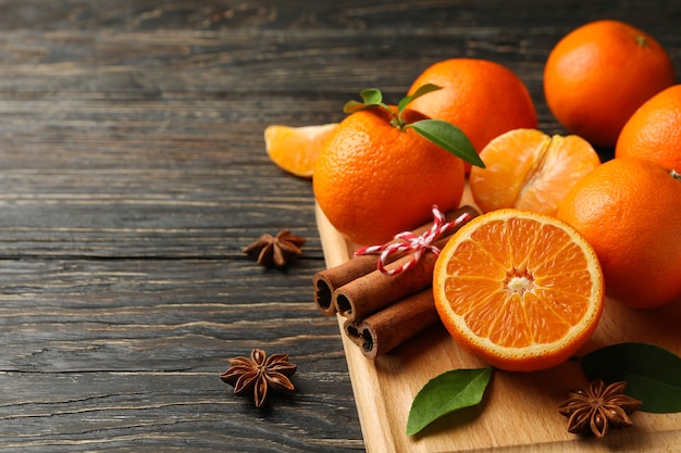 Board with mandarins and cinnamon on wooden