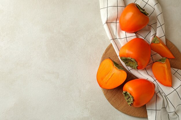 Board with persimmon and kitchen towel on white table