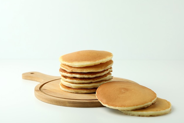 Board with tasty pancakes on white table