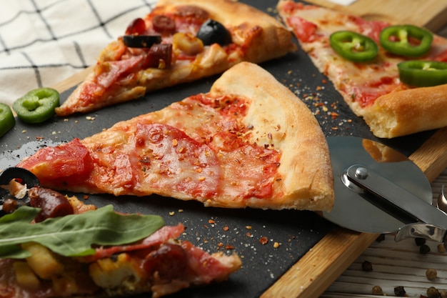 Board with tasty pizza slices on white wooden table