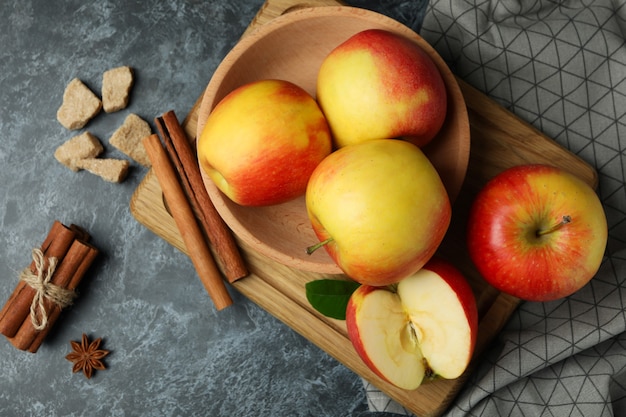 Board with tasty red apples on black smokey table