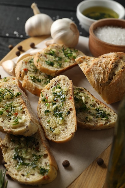 Board with toasted garlic bread and spices on wooden