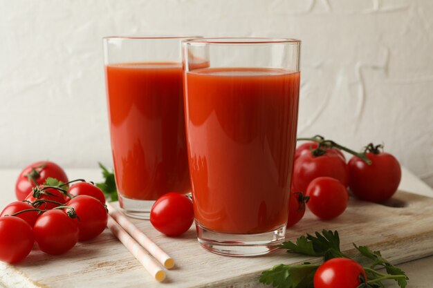 Доска с томатным соком и помидорами на белом текстурированном