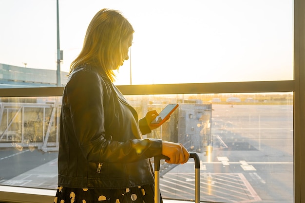 Boardingready a young woman with a suitcase checks her smartphone