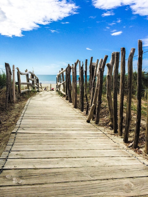 Photo boardwalk on beach against blue sky