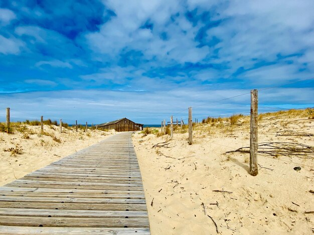 Boardwalk leading towards beach against sky