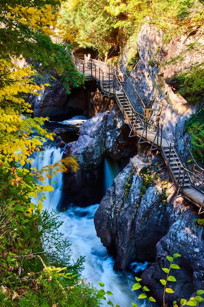 Boardwalk steps built into rocky cliffs of deep gorge with rapids waterfalls and fall colors