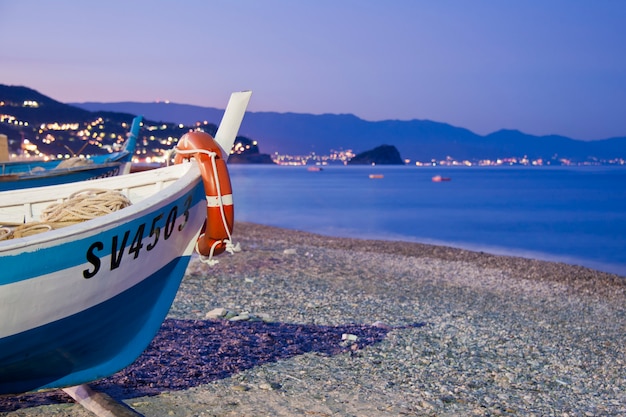 Foto barca sulla spiaggia di noli al tramonto