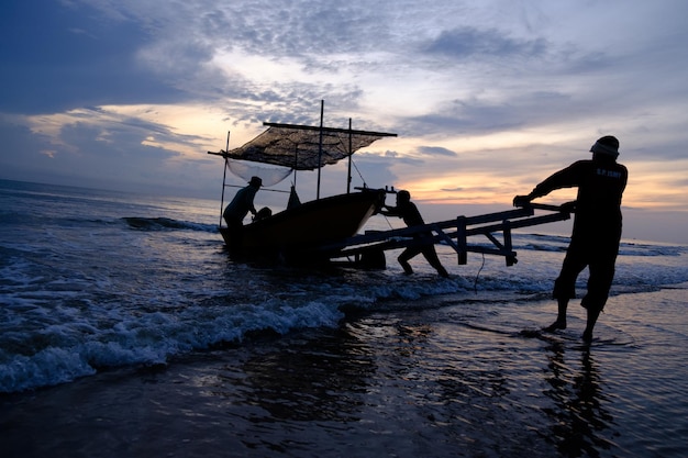 A boat on the beach with the sun setting behind it