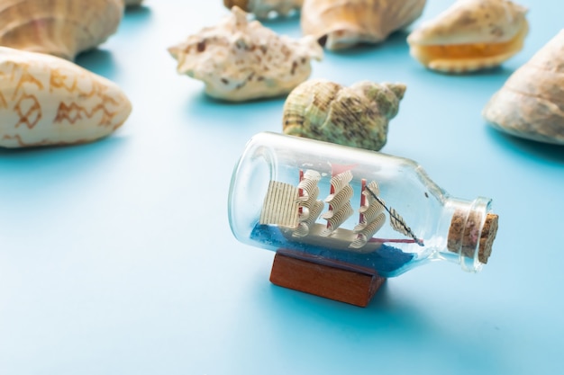 a boat in a bottle and seashells on a blue background